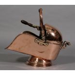 A VICTORIAN COPPER HELMET SHAPED COAL SCUTTLE with swing carrying handle and handle to back,