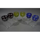 A set of six coloured hock wine glasses, line green, blue and ruby, on cut stems and circular bases,