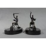 A pair of bronze sculptures of seated figures each reading a book in their left hand raising a