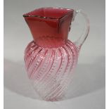 A Victorian shaded cranberry glass jug with square neck, clear loop handle,
