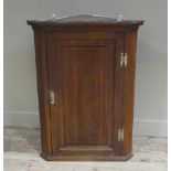 A George III oak hanging corner cupboard with dentil moulded cornice the door raised and fielded