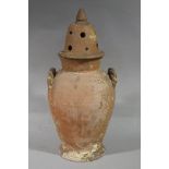 A terracotta vessel with pierced and domed cover and twin rope twist handles,