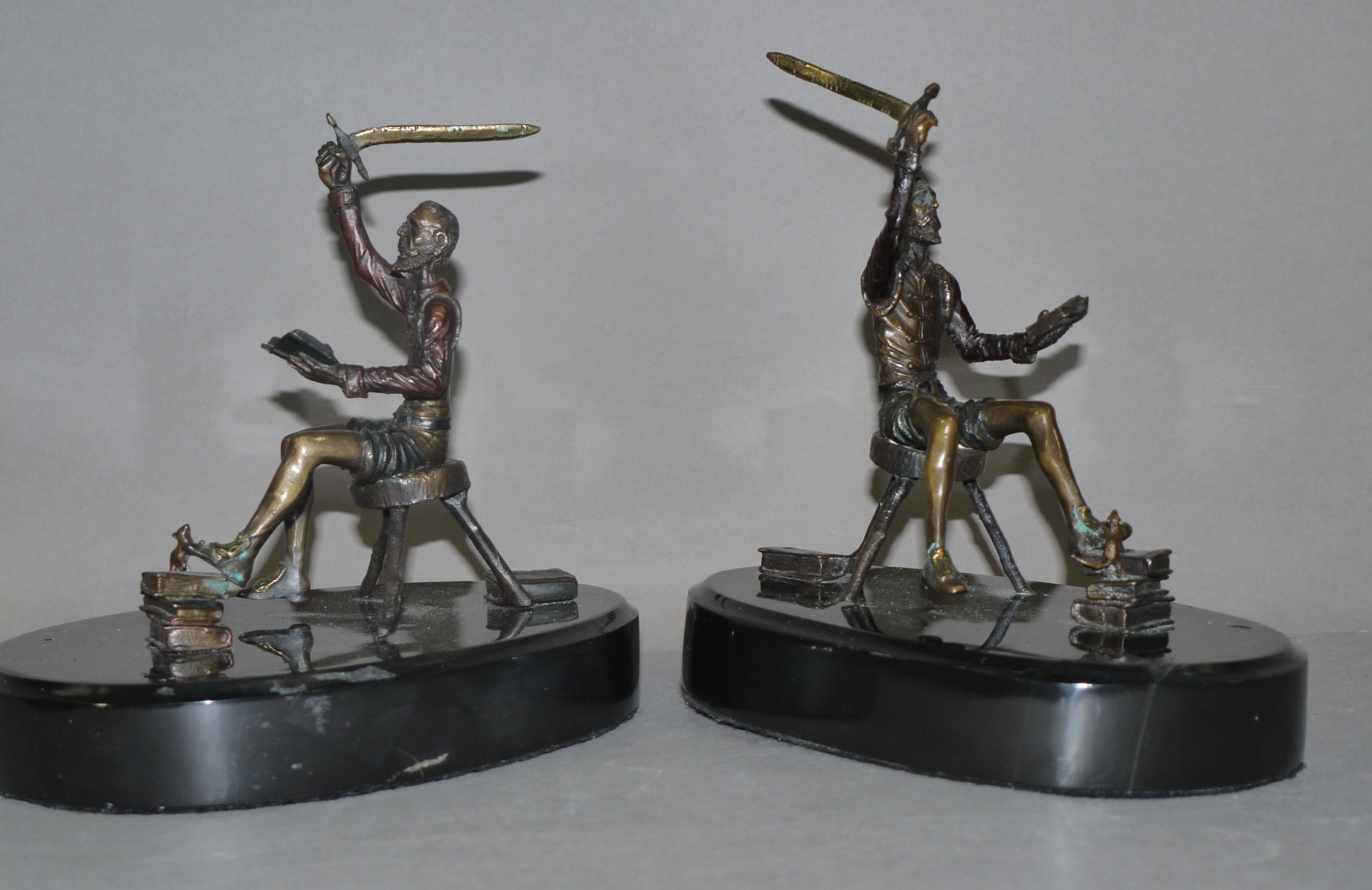 A pair of bronze sculptures of seated figures each reading a book in their left hand raising a - Image 2 of 3