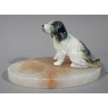 An oval alabaster ashtray mounted with a pottery dog figure,