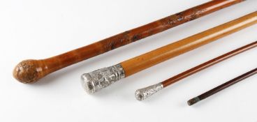 Group of Four Walking Sticks including two white metal topped Indian examples, one having figural