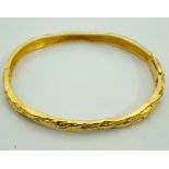 EIGHTEEN CARAT GOLD HINGED BANGLE with textured finish and safety catch,