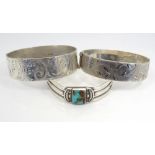 THREE SILVER BANGLES two with engraved floral and scroll decoration,