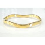 EIGHTEEN CARAT GOLD HINGED BANGLE of wavy design, approximately 13.
