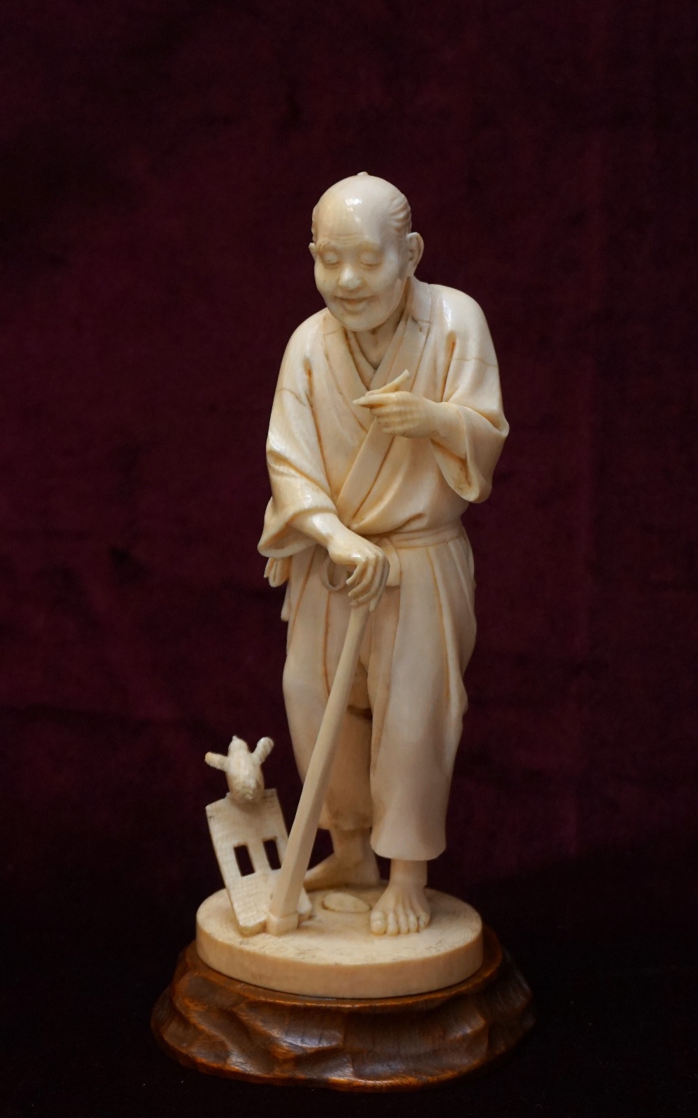 19th CENTURY JAPANESE CARVED IVORY OKIMONO depicting a farmer holding a hoe with a bird perched