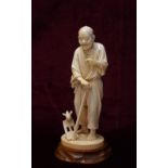 19th CENTURY JAPANESE CARVED IVORY OKIMONO depicting a farmer holding a hoe with a bird perched