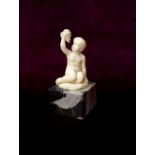 IN THE MANNER OF FERDINAND PREISS an early 20th century carved ivory figure of a seated boy holding
