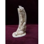 19th CENTURY JAPANESE CARVED IVORY OKIMONO depicting a seated man holding aloft part of the dragon