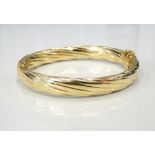 NINE CARAT GOLD HINGED BANGLE with twist decoration and safety clasp, approximately 15.