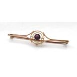 EDWARDIAN AMETHYST BAR BROOCH the central round cut amethyst in pierced concentric circular setting,