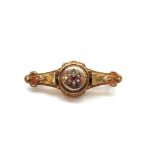 EDWARDIAN NINE CARAT GOLD MOURNING BROOCH the front with central ruby and seed pearl cluster,