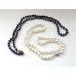 TWO CULTURED PEARL NECKLACES the black pearl example with fourteen carat gold clasp and