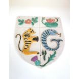 POTTERY HERALDIC SHIELD decorated in relief with a rose above a leopard and a water lily above a
