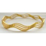 HIGH CARAT MIDDLE EASTERN GOLD BANGLE of pierced wavy design, bearing hallmarks,