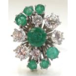 DECORATIVE EMERALD AND CZ SET DRESS RING the central larger emerald surrounded by smaller stones,