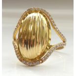 TWENTY-ONE CARAT GOLD RING the central textured oval panel with clear stones above and below