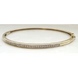 DIAMOND SET GOLD BANGLE the channel set diamond to one side of the hinged bangle, in unmarked gold,