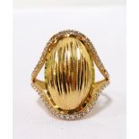 TWENTY-ONE CARAT GOLD RING the central textured oval panel with clear stones above and below