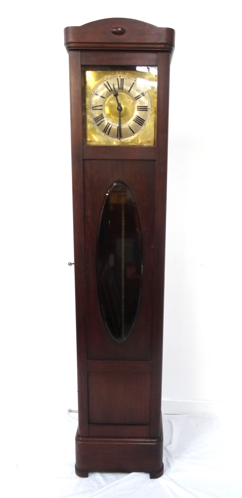 1920s MAHOGANY LONGCASE CLOCK with a brass dial and a silvered chapter ring with Roman numerals,