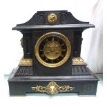 VICTORIAN BLACK SLATE MANTLE CLOCK with a shaped top applied with a gilt metal plaque above a