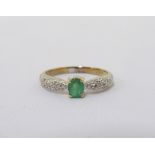 EMERALD AND DIAMOND RING the central oval cut emerald flanked by pave set diamond shoulders,