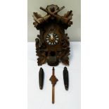 BLACK FOREST CUCKOO CLOCK with carved oak leaves and guns to the pediment above a panelled door