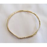 NINE CARAT GOLD BANGLE of wavy design and with textured decoration, approximately 9.