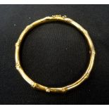 EIGHTEEN CARAT GOLD BANGLE of bamboo design, with safety chain, approximately 12.