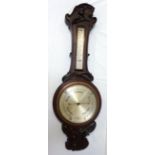 MAHOGANY BAROMETER with a shaped carved top decorated with a tulip above a thermometer with a