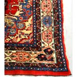 LARGE IRANIAN WOOLLEN CARPET the central design within a decorative border, in reds and blues,