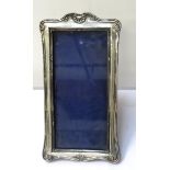 EDWARDIAN TALL SILVER PHOTOGRAPH FRAME with shell motif decoration, on easel support,
