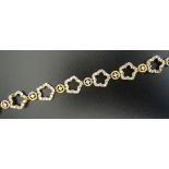 TWENTY-ONE CARAT GOLD CZ SET BRACELET with alternating flower shaped and circular links,