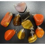 SELECTION OF TEN POLISHED AGATE AND HARDSTONE PENDANTS including tiger's eye,