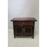 AN ORIENTAL BLACK AND RED PAINTED SIDE CABINET, the rectangular top with two frieze drawers,