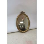 A GILT FRAMED OVAL MIRROR,