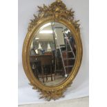 A CONTINENTAL GILT CARVED OVAL OVERMANTLE MIRROR,