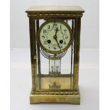 An Edwardian brass mantel clock, the white dial with Arabic numerals denoting hours, eight day