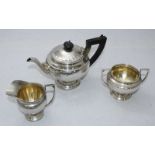 A three-piece silver tea set comprising teapot with ebonised handle and finial on spreading foot,