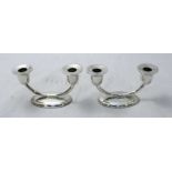 A pair of .900 grade silver two light candelabra, raised on oval bases.