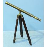 A brass telescope on wooden and brass adjustable tripod base