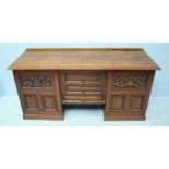 An Edwardian walnut low sideboard, with three central short drawers flanked by two carved cupboard