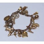 A 9ct gold charm bracelet with multiple charms including a penny farthing and an articulated fish.