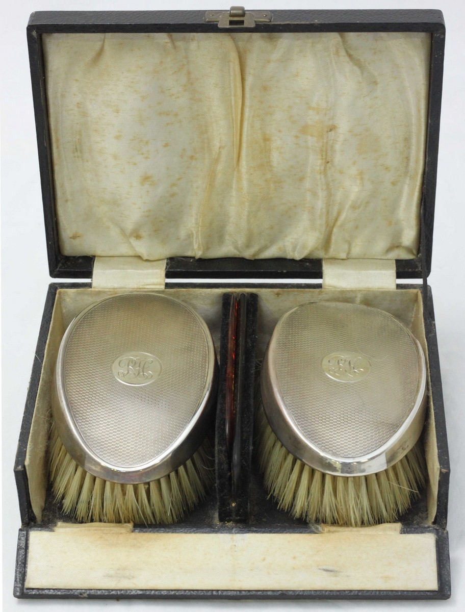 A cased dressing table set comprising silver backed brushes and two combs, maker's mark Hasset &