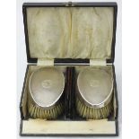 A cased dressing table set comprising silver backed brushes and two combs, maker's mark Hasset &