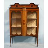 An Edwardian inlaid mahogany two door display cabinet, the raised back above two glazed doors