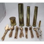 Five brass artillery shell cases and a yellow metal cutlery set with simulated bamboo handles.